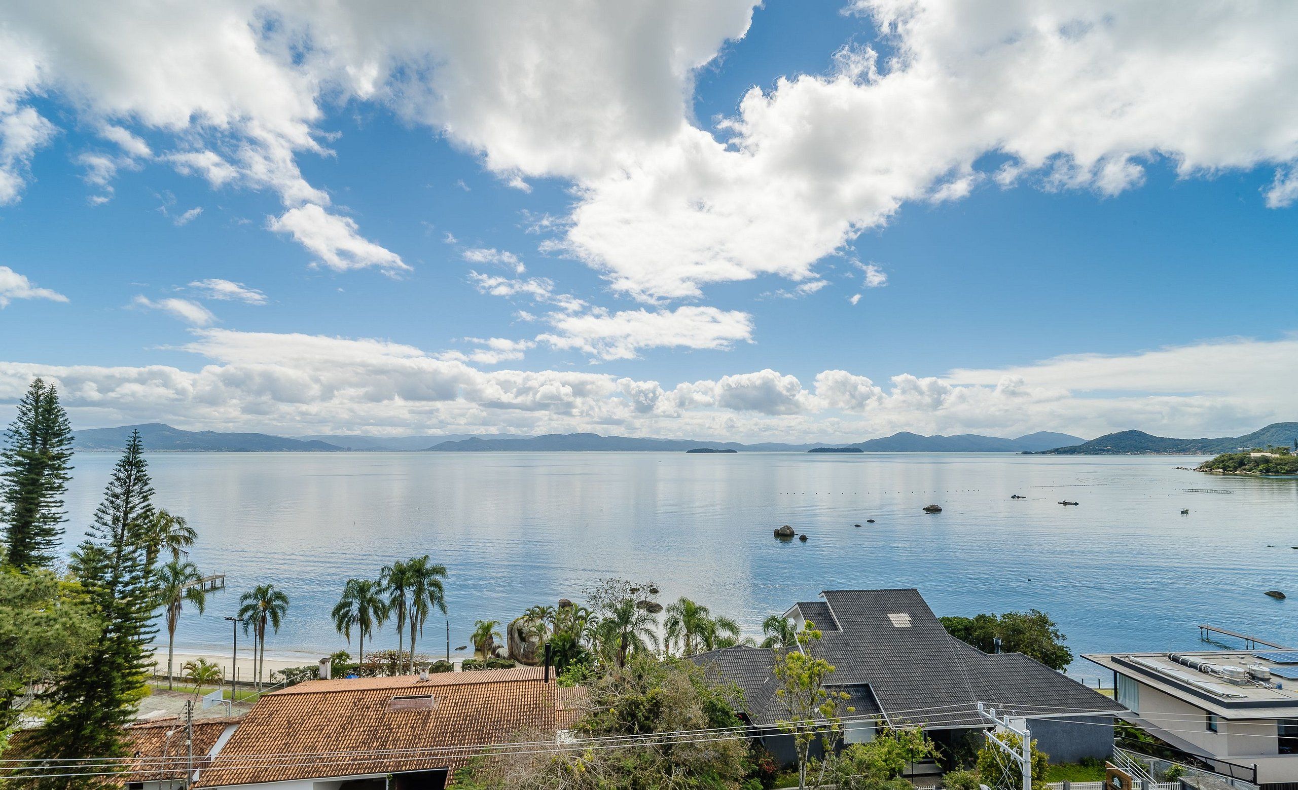 A coastal residential area with houses, a clear sky, and calm water.
