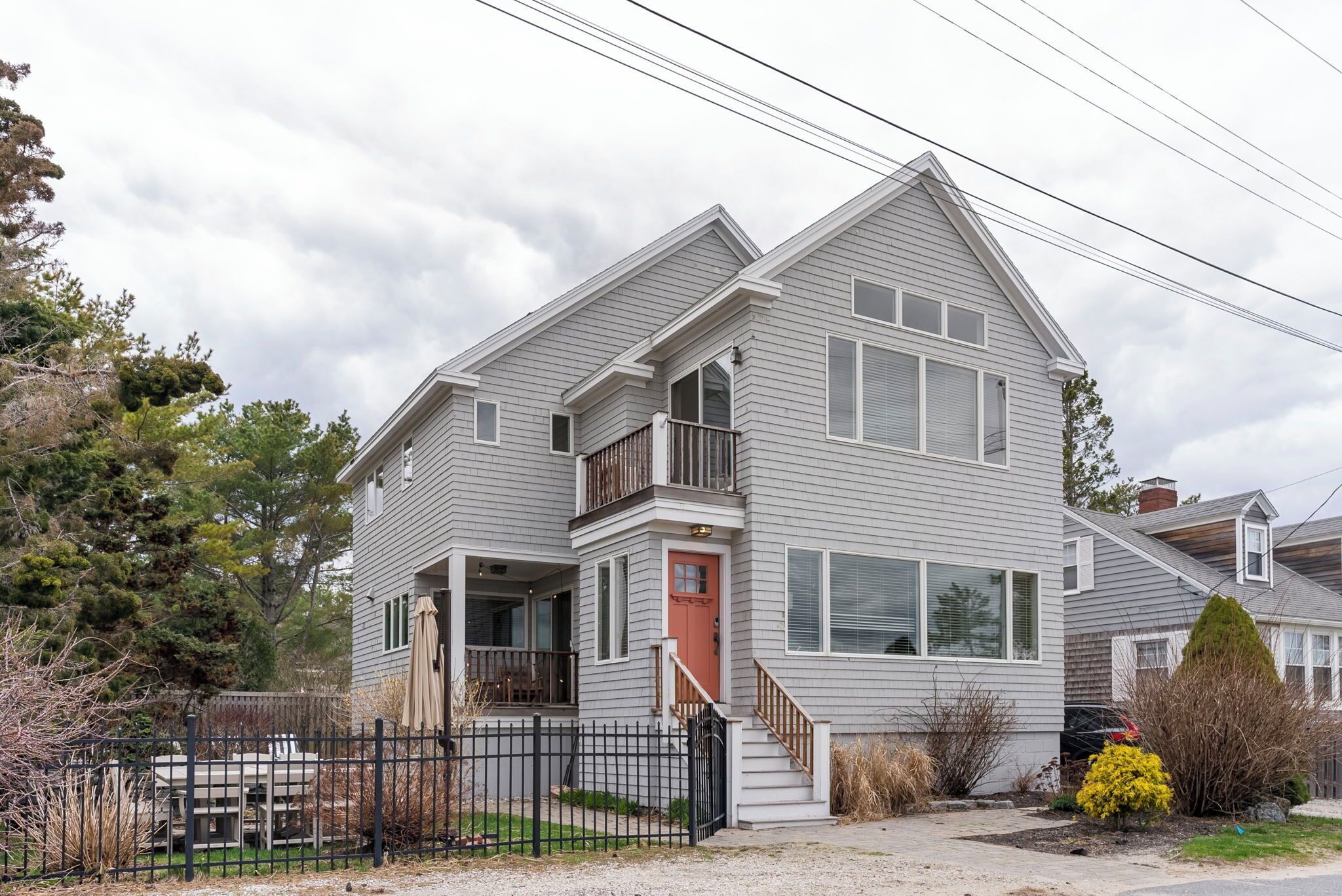 A two-story house with a front porch, a small balcony, and a red door.