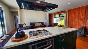 Een moderne keuken met een centraal kookeiland, een inbouwoven en een gasfornuis.