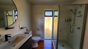 Een moderne badkamer met een grote spiegel, een wastafel, een toilet en een douchecabine met glazen wanden.