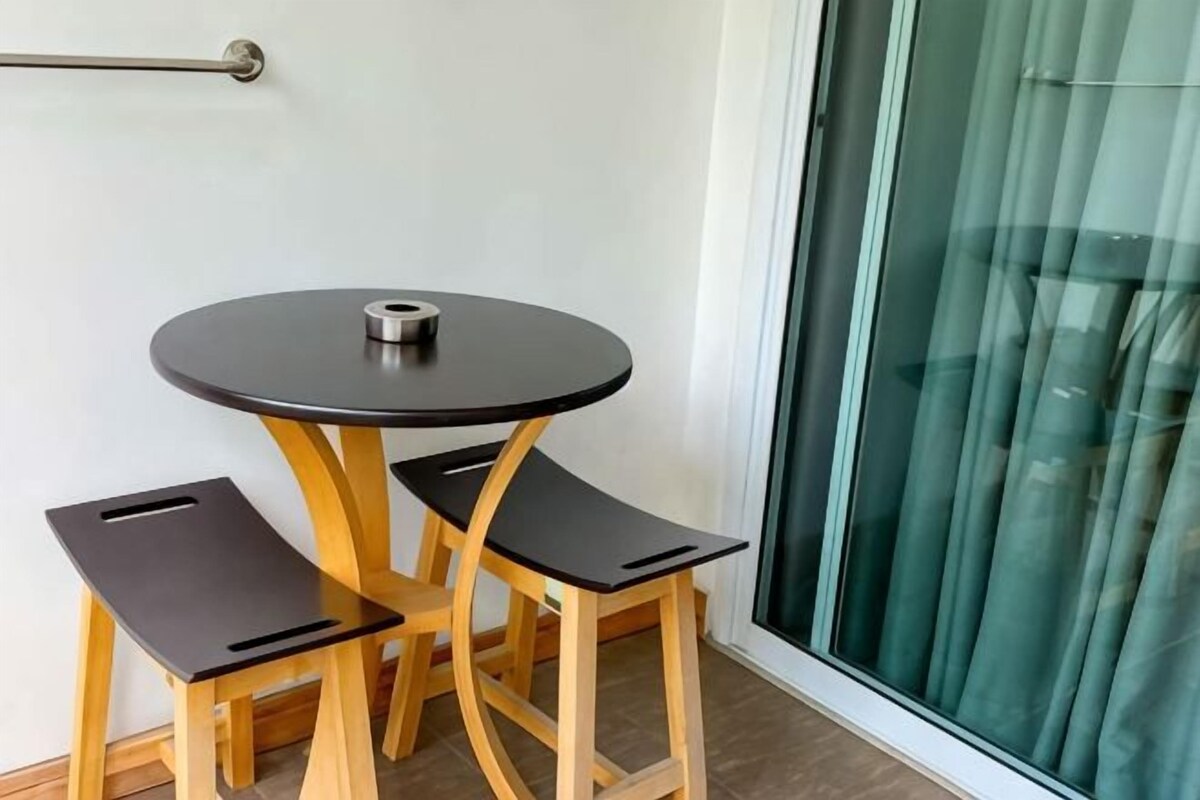 A small round table with a black top and two black chairs, positioned near a sliding glass door.