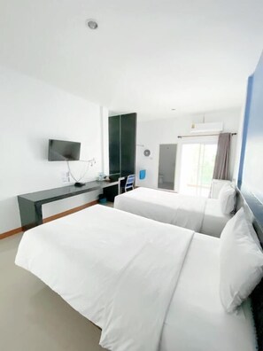 A hotel room with a bed, a desk, a TV, and a window with curtains. - Tanatnan Hotel (Ranong)