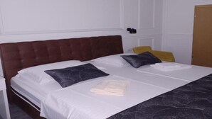 Una habitación de hotel con una cama grande, cabecera de madera, mesita de noche y lámpara colgante.
