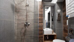 Un baño moderno con ducha de vidrio, lavamanos blanco y un inodoro.