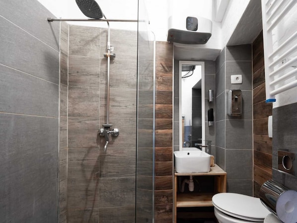 A modern bathroom with a glass-enclosed shower, a white sink, and a toilet.