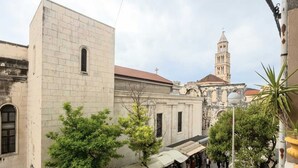 Una calle estrecha con edificios, una torre de campanas y puestos de mercado al aire libre.