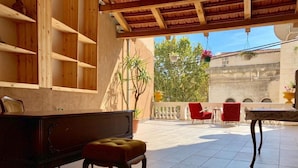 Un patio amplio con un banco de madera, una mesita y sillas rojas.