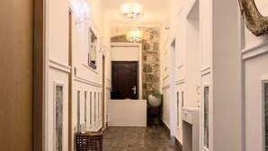 Un pasillo con pared de piedra, un candelabro y una puerta al final.