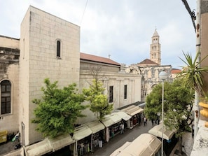 Une rue étroite bordée d’immeubles, avec un clocher et des étals de marché en plein air.