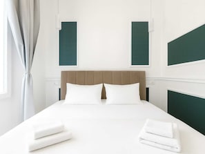 Une chambre d’hôtel avec un lit, deux fenêtres et une vue sur l’extérieur.