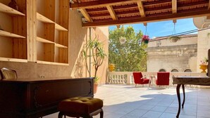 A spacious patio with a wooden bench, a small table, and red chairs.