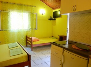 Une petite pièce aux couleurs vives, comprenant un lit, un bureau et une kitchenette.