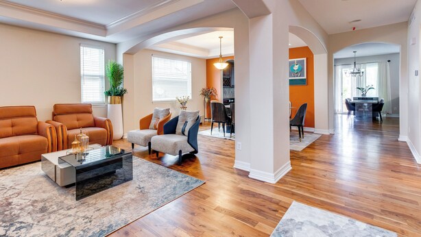A spacious living room with hardwood flooring, a glass coffee table, and a seating area with sofas and chairs. - Yard, Home Gym, & Game Room: Spacious Aurora Home (Aurora)