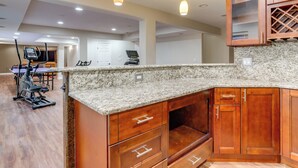 A kitchen with granite countertops, wooden cabinets, and a built-in wine rack. - Yard, Home Gym, & Game Room: Spacious Aurora Home (Aurora)