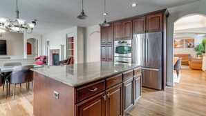 A modern kitchen with wooden cabinets, stainless steel appliances, and a granite countertop. - Yard, Home Gym, & Game Room: Spacious Aurora Home (Aurora)