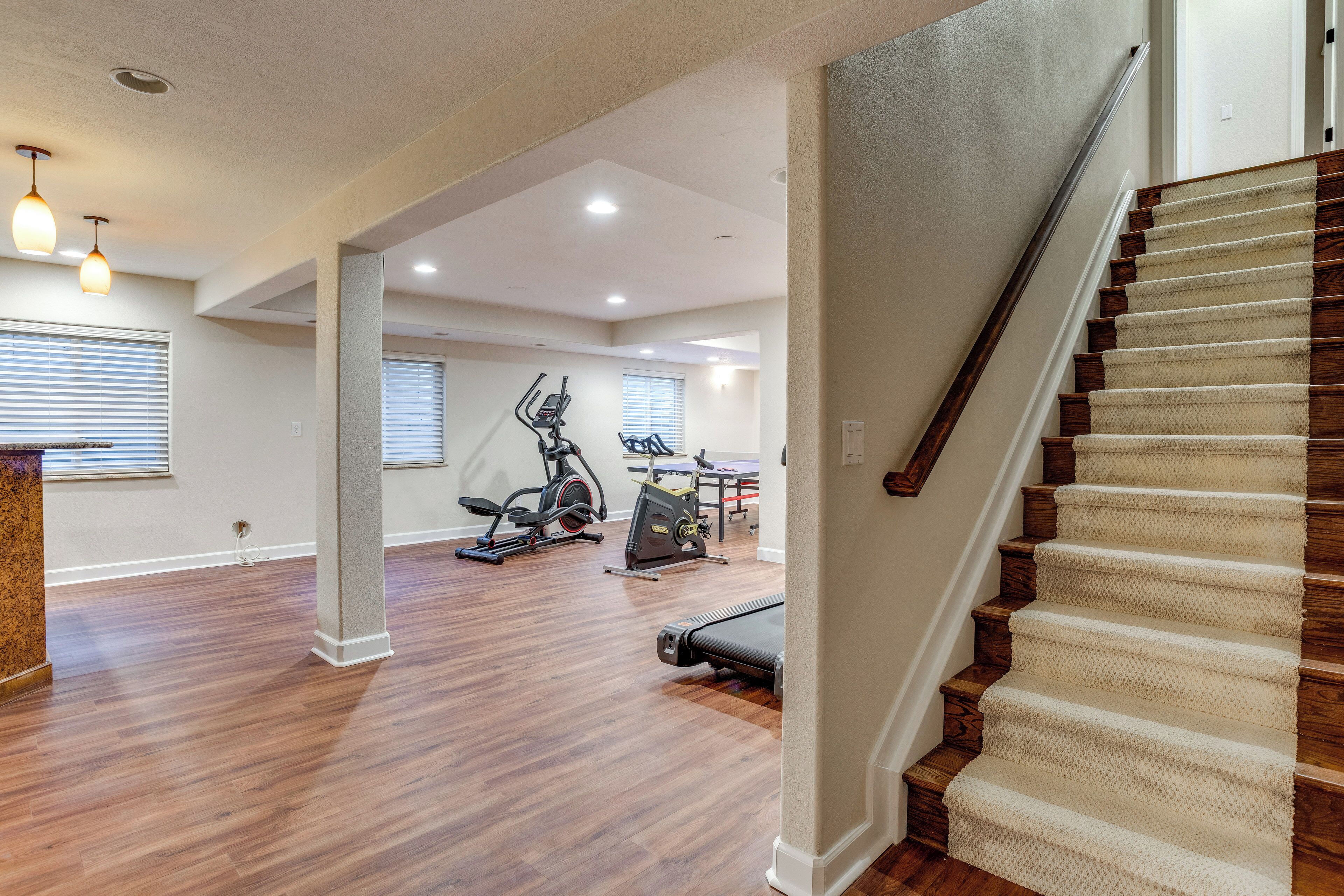 A spacious living area with hardwood flooring, a staircase, and exercise equipment.