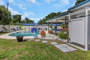 A backyard with a swimming pool, lounge chairs, and a covered patio area. - Relax Home with Pool and near Beaches in Largo, FL (Largo)