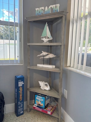 A shelf with a sailboat model, a wooden tumbling tower box, and a family bingo game box.