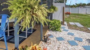 A covered patio area with a white ceiling, a blue metal chair, and a variety of potted plants. - Relax Home with Pool and near Beaches in Largo, FL (Largo)