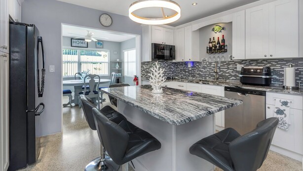 A modern kitchen with a central island, bar stools, a refrigerator, and a microwave. - Relax Home with Pool and near Beaches in Largo, FL (Largo)