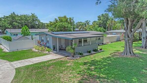A single-story house with a covered patio, solar panels, and a well-maintained lawn. - Relax Home with Pool and near Beaches in Largo, FL (Largo)