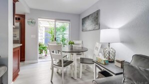 Un salon moderne comprenant un coin repas, un canapé, une lampe et une vue sur la verdure à l’extérieur.