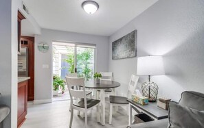 Una sala de estar moderna con comedor, un sofá, una lámpara y vistas a zonas verdes.