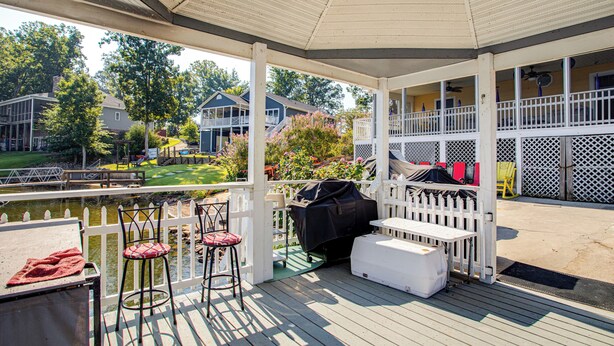 A covered outdoor deck with a grill, two bar stools, and a table. - Bring Your Boat! Lake Murray Home w/ Dock & Ramp (Prosperity)