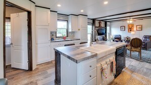 A modern kitchen with white cabinetry, a central island, and a dining area with a chair and table. - Peaceful Countryside Home w/ Yard in Hawley (Hawley)