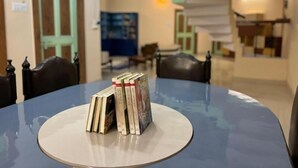 Ein runder Tisch mit einer Bücherstapel in der Mitte, umgeben von Stühlen.