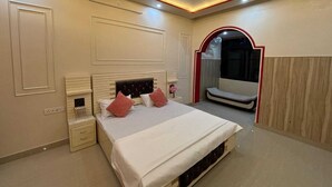 Ein Schlafzimmer mit Bett, Nachttischen, einem Spiegel und einer kleinen Sitzecke.