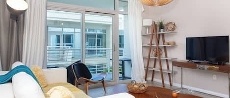 Una sala moderna con un sofá, sillas, un televisor y vistas al balcón.