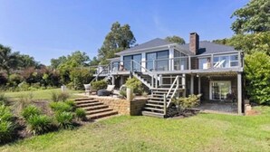 A two-story house with a covered patio, a staircase, and a small garden area. - Beautiful waterfront house located in Hampstead, NC (Hampstead)
