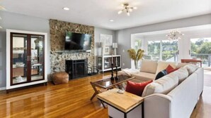 A spacious living room with a stone fireplace, a large flat-screen TV, a sofa, and a coffee table. - Beautiful waterfront house located in Hampstead, NC (Hampstead)