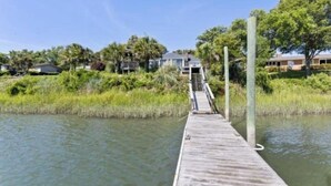 A wooden pier extending into a body of water with a staircase leading to a building in the background. - Beautiful waterfront house located in Hampstead, NC (Hampstead)