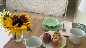 Une table de petit-déjeuner soigneusement dressée, avec un vase rempli de tournesols, une assiette de pommes et divers bols et tasses.