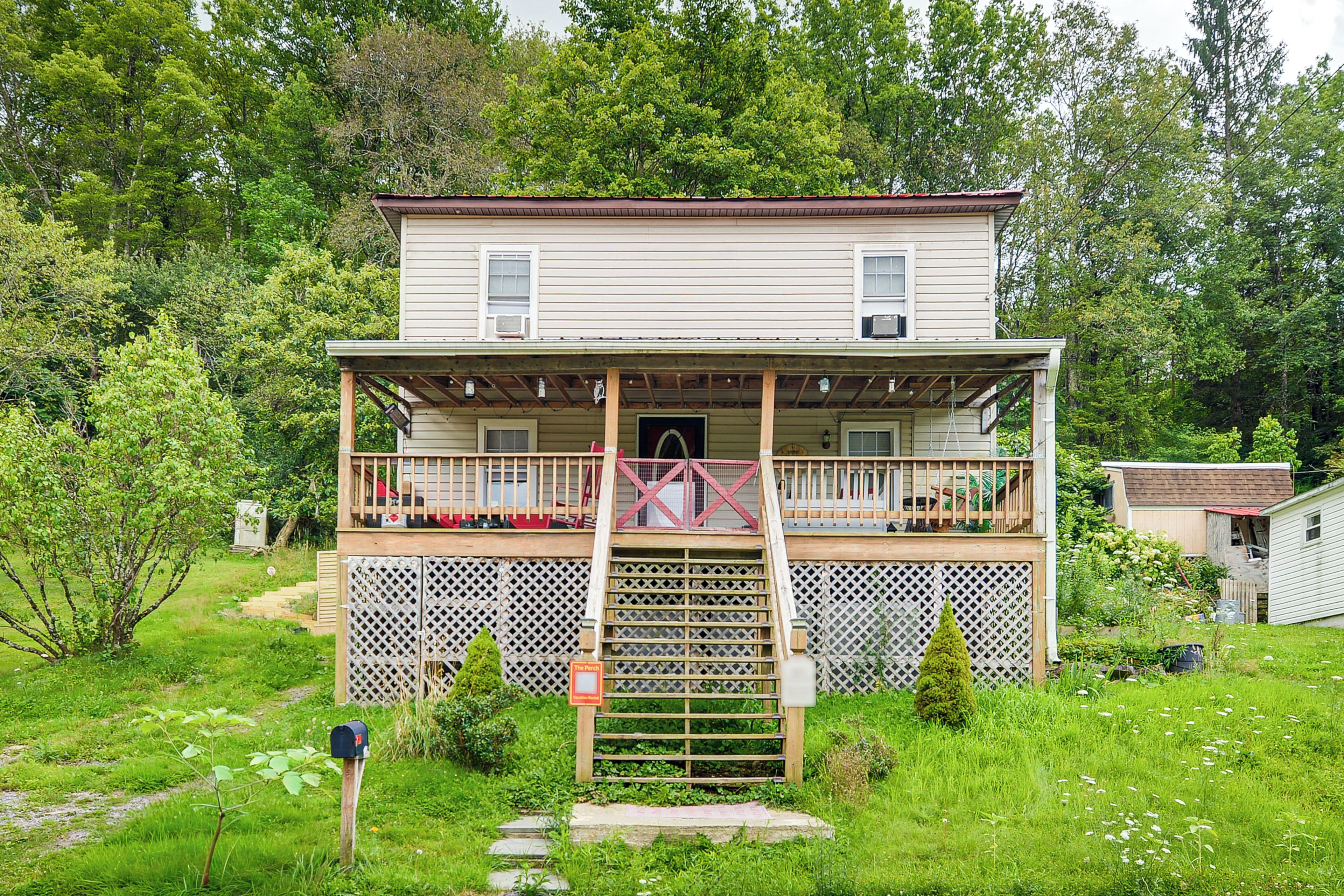A two-story house with a front porch, a wooden deck, and a fenced yard.