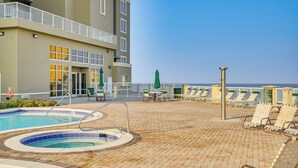 A pool area with lounge chairs and a building with a balcony.