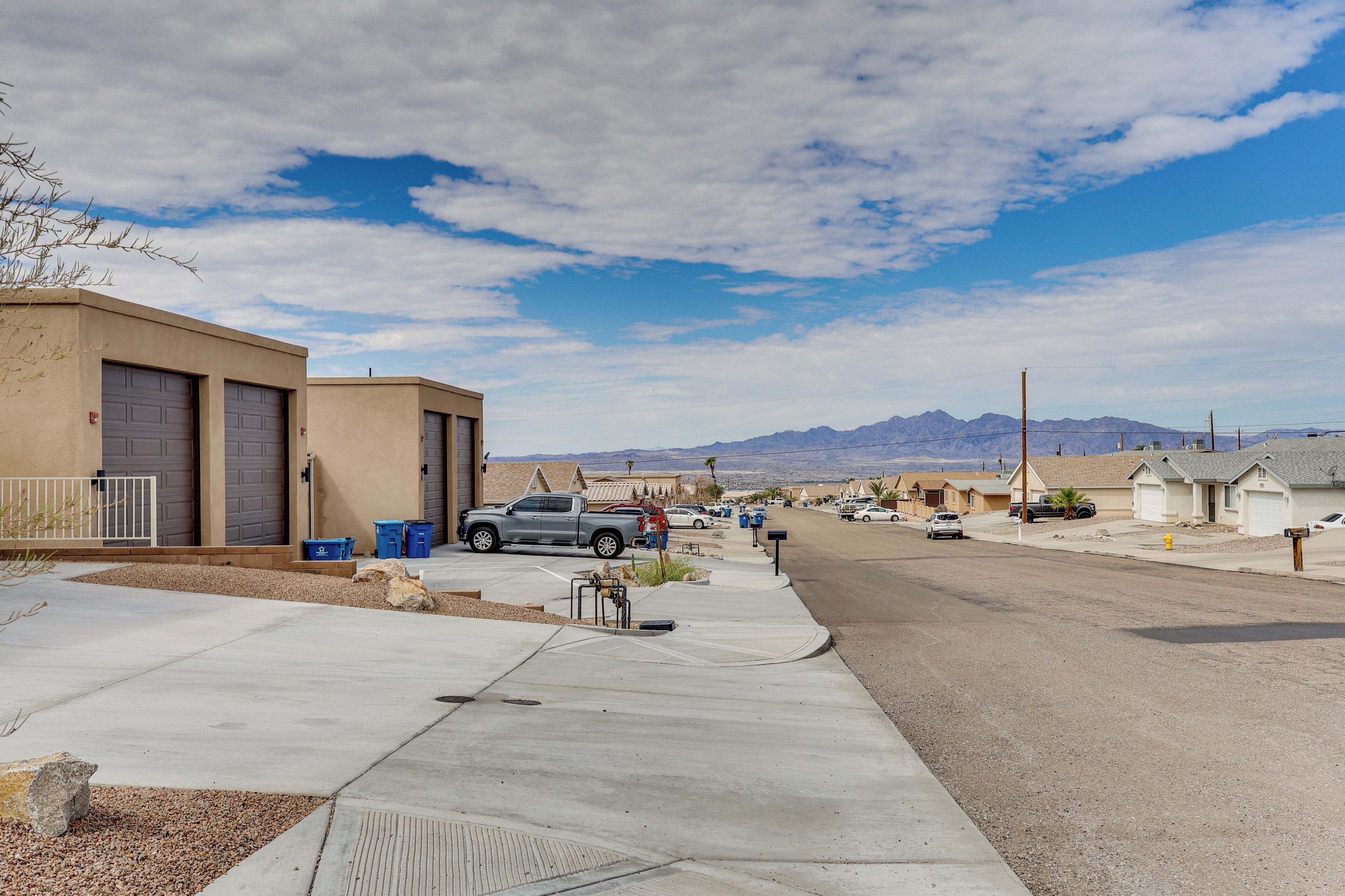 A residential street with houses, a parked truck, and mountains in the background.