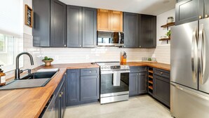 A modern kitchen with dark cabinetry, stainless steel appliances, and a wooden countertop. - 'The High Country Hideaway' Flagstaff Golf Retreat (Flagstaff)