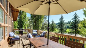A wooden deck with a table and chairs, an umbrella, and a view of trees and hills. - 'The High Country Hideaway' Flagstaff Golf Retreat (Flagstaff)