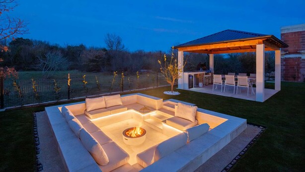 A well-lit outdoor seating area with a fire pit, a covered patio, and a view of a natural landscape. - Villa Neoma – Tranquil Seaside Escape with Heated Pool and Breathtaking Sea Views (Linardići (Krk))