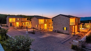 A residential area with multiple houses, each with a well-lit entrance and visible balconies. - Villa Pinaza B – Romantic Seaside Retreat with Heated Pool, Sauna, and Jacuzzi in Vrbnik (Vrbnik (Krk))