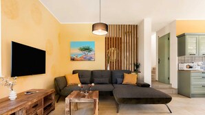 A living room with a sectional sofa, a wooden coffee table, and a flat-screen TV mounted on the wall. - Villa Pinaza B – Romantic Seaside Retreat with Heated Pool, Sauna, and Jacuzzi in Vrbnik (Vrbnik (Krk))