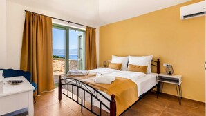 Quarto de hotel com cama, escrivaninha, cadeira e vista para o mar.