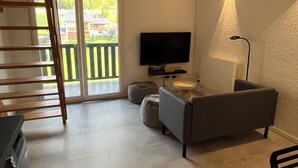 Un soggiorno moderno con un divano, una TV a schermo piatto, una lampada e un soffitto in legno.