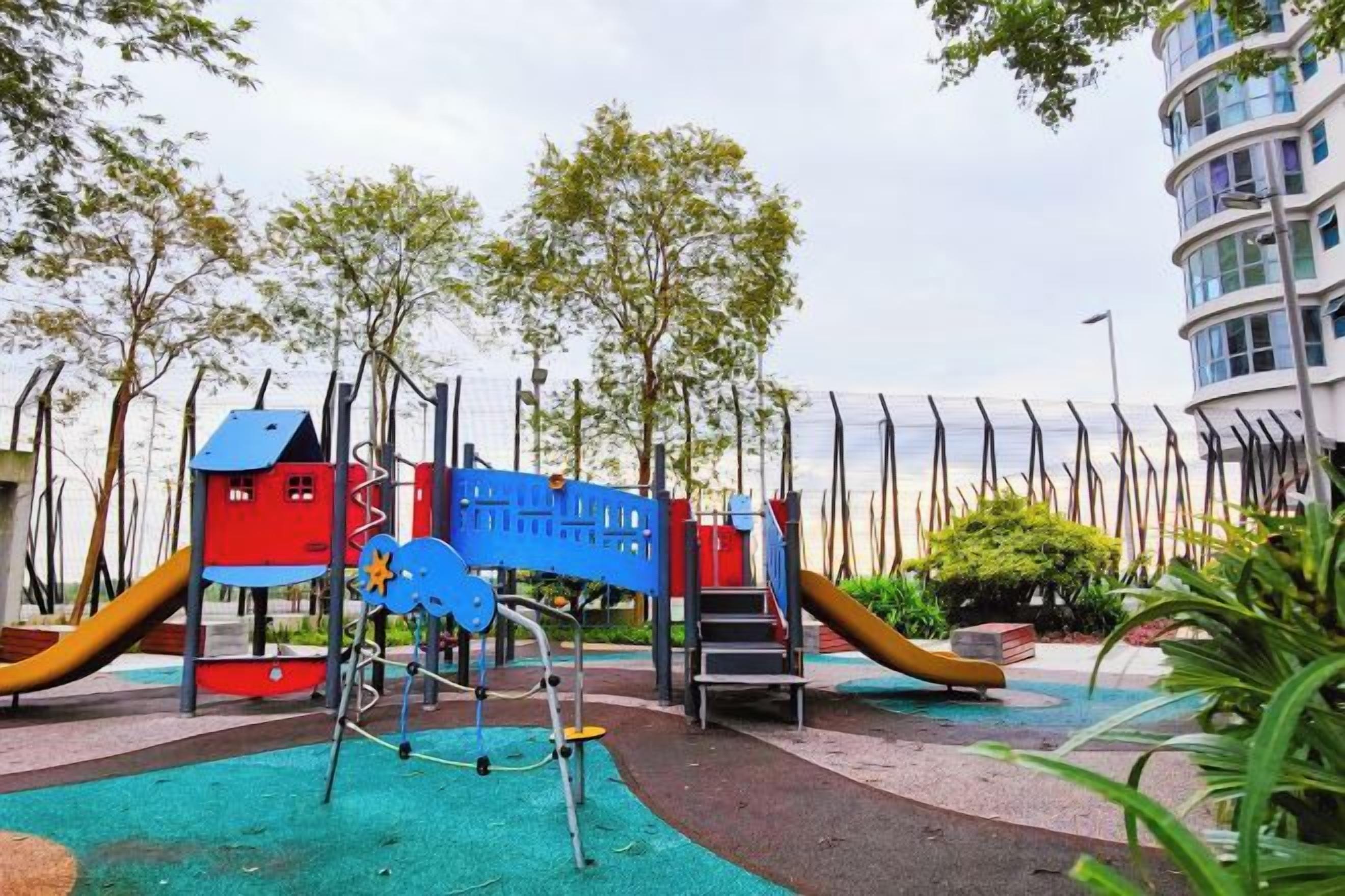 A playground with various play structures, surrounded by trees and a building.