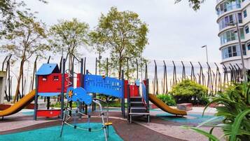 A playground with various play structures, surrounded by trees and a building.