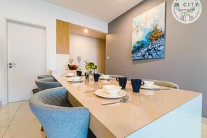 Uma sala de jantar moderna com uma mesa comprida, cadeiras e um quadro na parede.