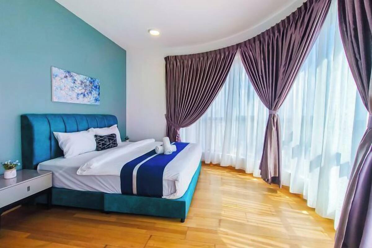 Una camera da letto moderna con un letto grande, un comodino, un quadro appeso al muro e vista attraverso tende leggere.